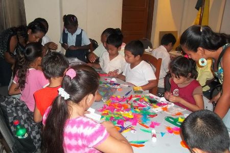 volunteers working with a table of children helping make arts and crafts