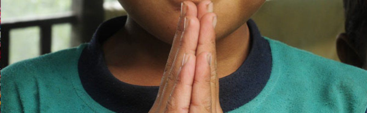 close up of child praying with hands together