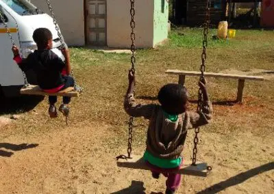 Pre-school children using swings constructed on volunteer building project Swaziland