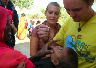 Volunteers helping mother giving her son eyedrops in underprivileged community