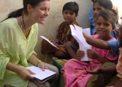 Volunteer kneeling down teaching children in Indian classroom