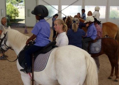 Volunteers leading children equine therapy for disabled children South Africa
