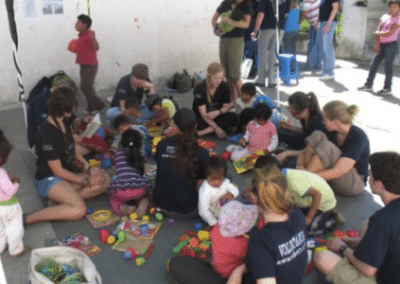 Volunteers sat with children education outreach for child workers Ecuador