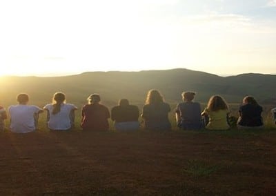 group of volunteers sitting in a line looking out to the sunset