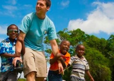 Volunteer holding hands with children community sports coaching South Africa