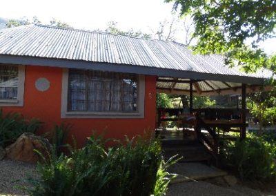 A small orange house in Africa with a metal roof.
