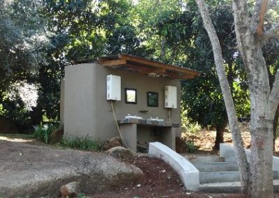 A small concrete building with trees in the background.