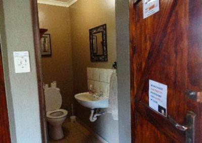 A bathroom with a toilet and a mirror above the sink.
