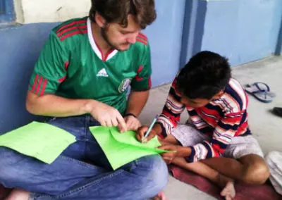 Volunteer and boy reading Volunteering for 16 and 17 year olds in India