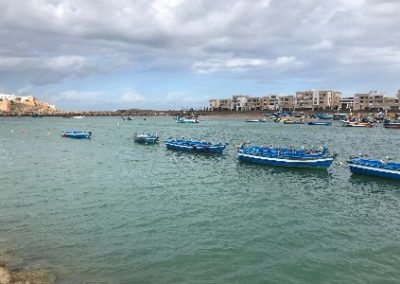 Boats moored in calm waters beside a bustling city.