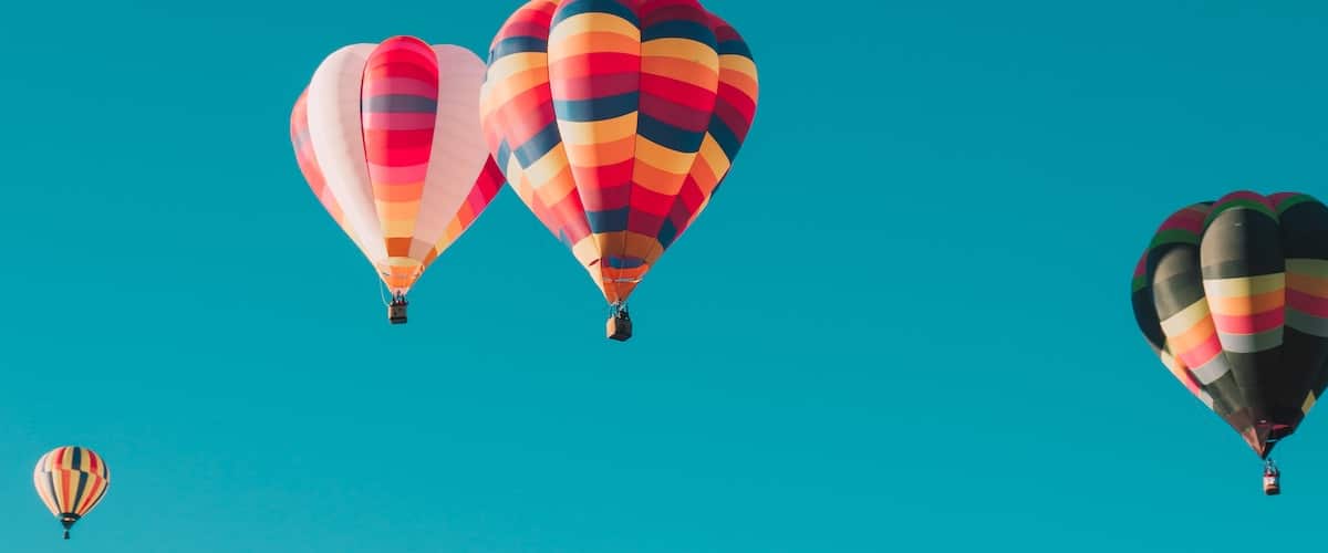 ian-dooley-hpTH5b6mo2s-unsplash colourful hot air balloons in the blue sky