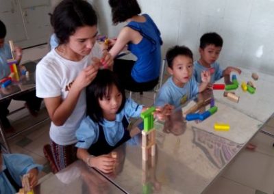Volunteers with children playing with colorful wooden blocks.