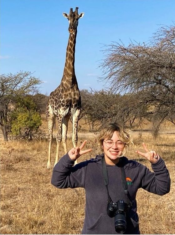 Intern in front of giraffe in Zimbabwe