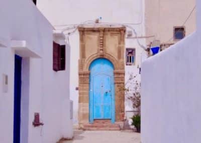 blue door at the end of a white walled street