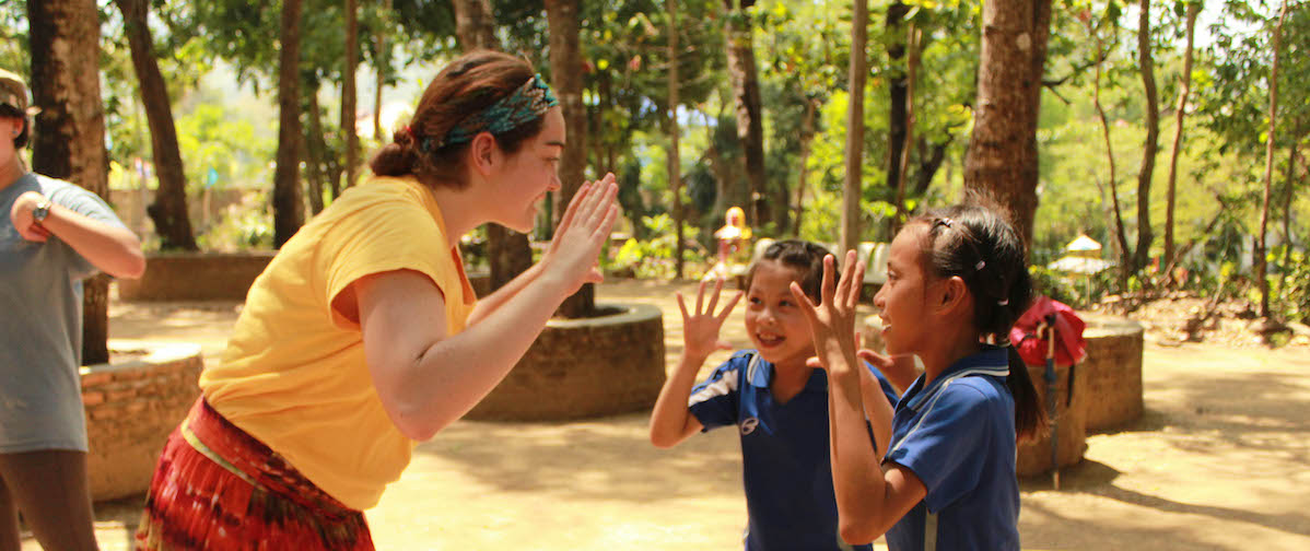 Thailand community vol with children volunteer with two girls from the community acting out a song