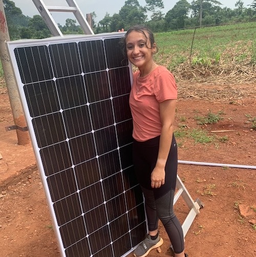 volunteer working on a sustainable energy project in uganda posing with a solar panel