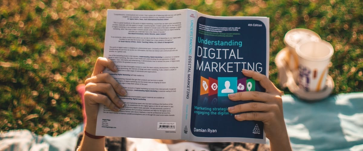 elio-santos-M38gjx6hifY-unsplash intern reading marketing book on the grass