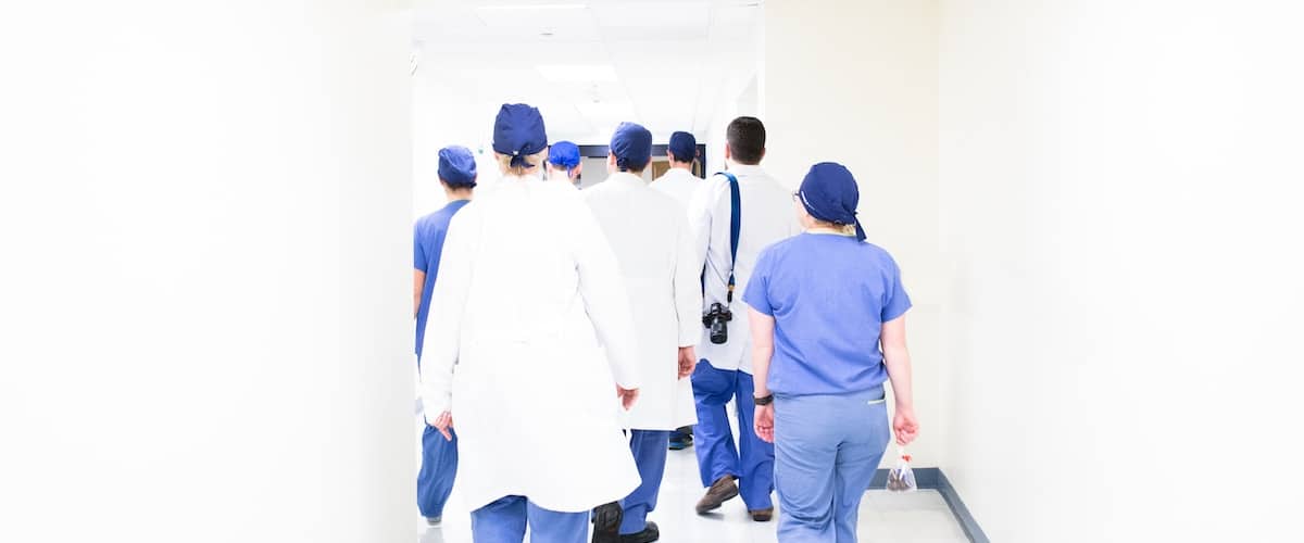 health care workers walking in scrubs through corridor 