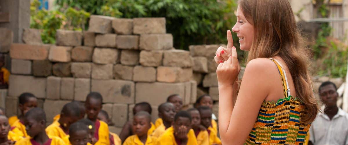 young woman gestures with her finger in front of a group of children