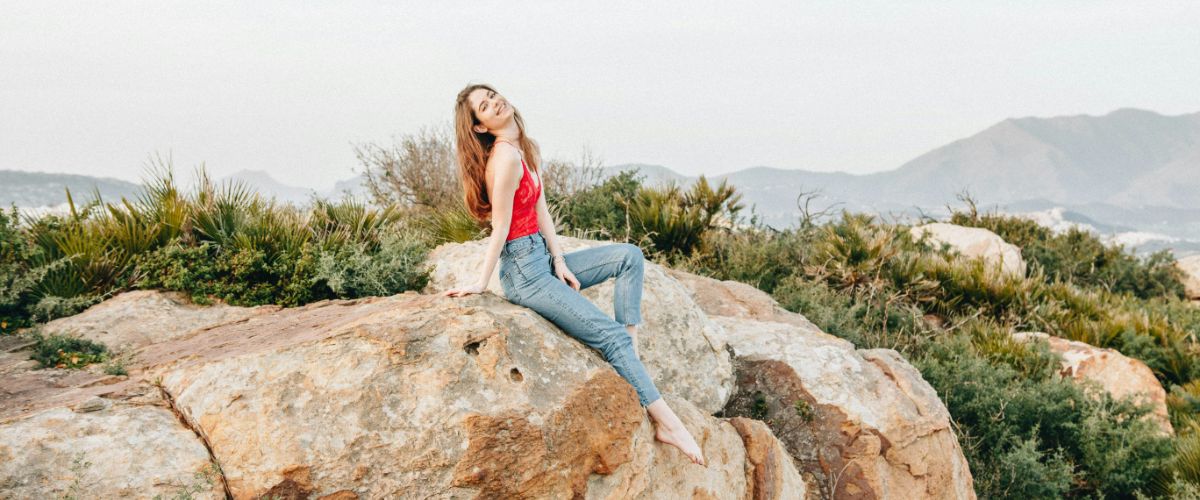 Woman sitting on a rock in nature, smiling